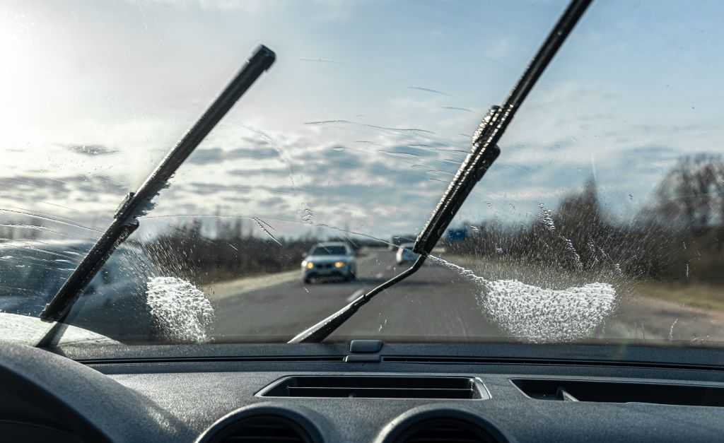 Car wipers clean windshields when driving in sunny weather.
